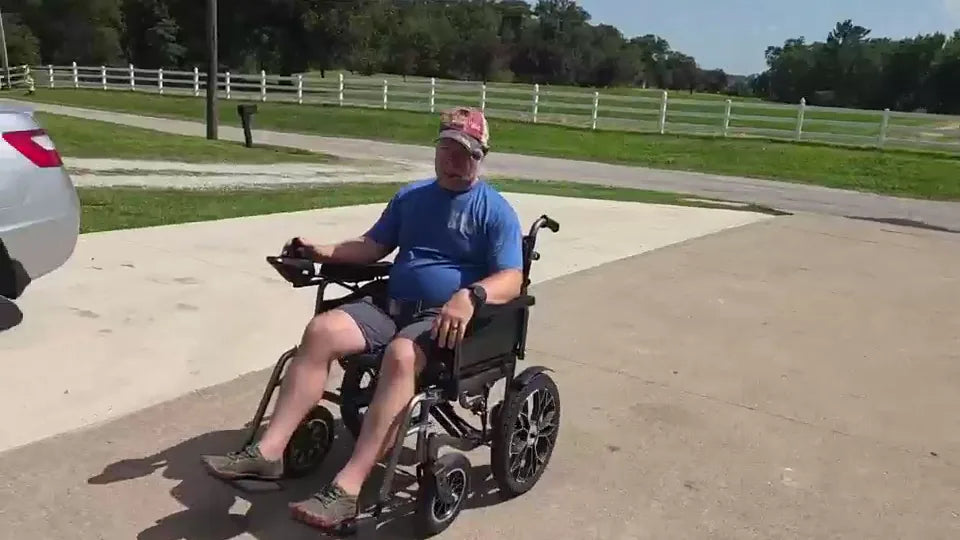 Real YS16-1 MAX rider seated outdoors with both feet fully supported on the wheelchair foot supports.